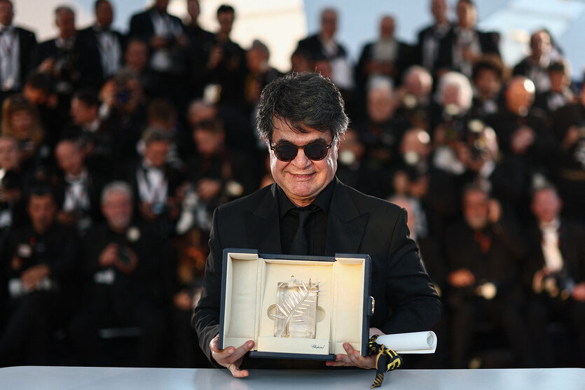 Der Regisseur Jafar Panahi mit Sonenbrille und schwarzem Anzug streckt dem Publikum die "Goldene Palme" entgegen und lächelt