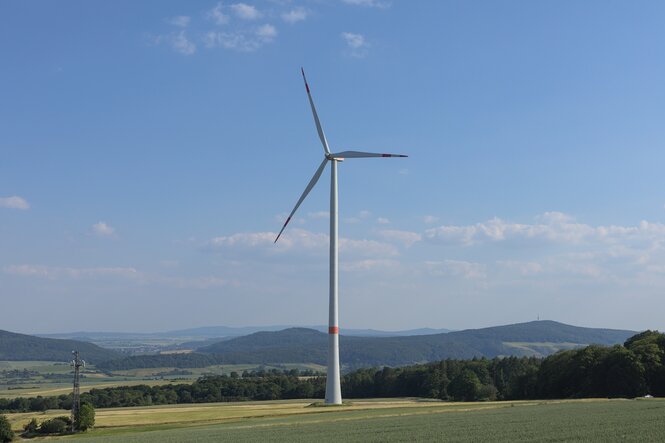 Ein Windrad steht in einer hügeligen Landschaft