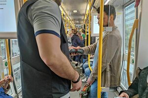 Eine Szene aus einer Tram während einer Ticketkontrolle, der Kontrolleur hält sein Lesegerät an das digitale Ticket eines Mannes