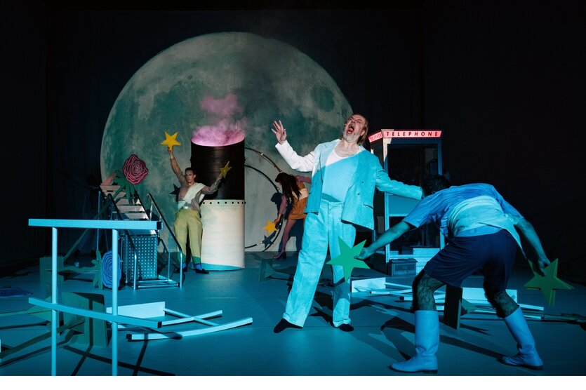 Schreiende und mit Sternen spielende Personen auf einer Theaterbühne