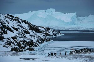 Eine Gruppe Touristen wandert in der Nähe des grönländischen Ortes Ilulissat vor der Kulisse riesiger Eisberge entlang. Die Eisberge sind vom nahegelegenen Gletscher Sermeq Kujalleq gekalbt