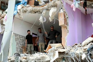 Menschen stehen in einem halb zerstörten Haus