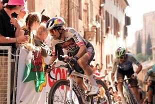 Roglic fährt um die Kurve, Absperrgitter und Zuschauer sind zu sehen