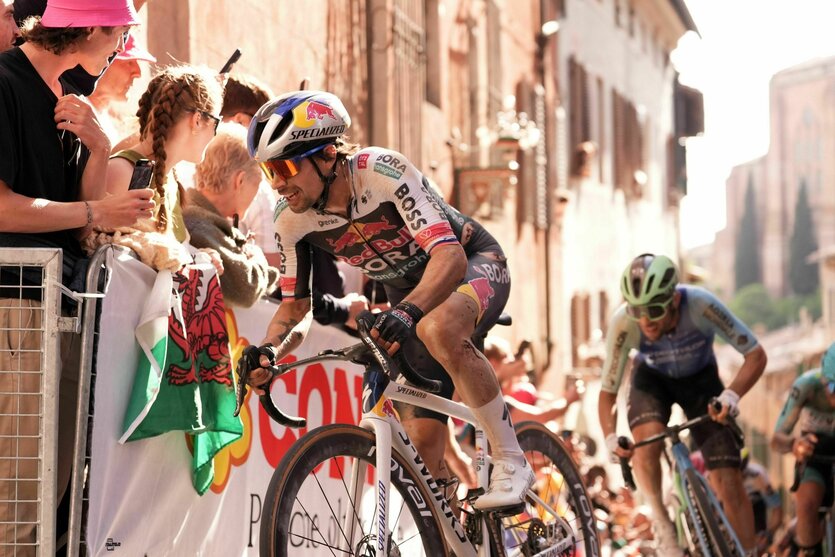 Roglic fährt um die Kurve, Absperrgitter und Zuschauer sind zu sehen
