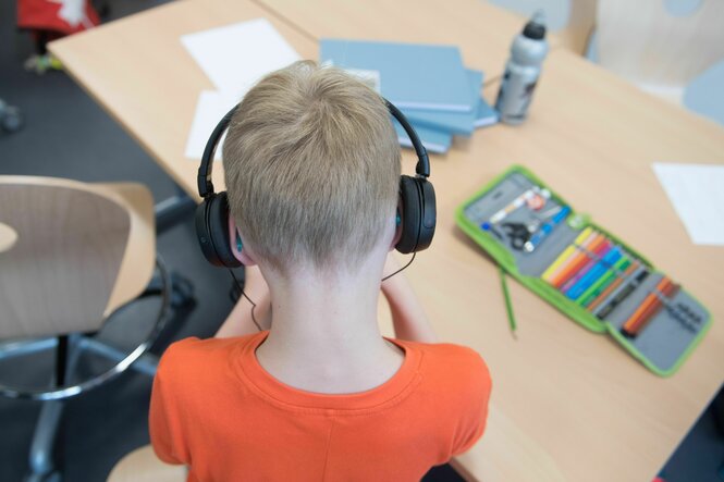 Kind mit Kopfhörer im Klassenzimmer