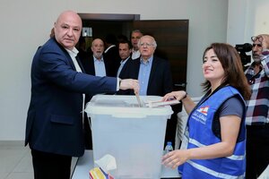 Der libanesische Präsident Joseph Aoun steht vor einer Wahlurne und wirft seinen Wahlzettel ein, ein junge Frau überwacht den Vorgang