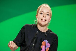 Eine Frau steht an einem Rednerpult und spricht ins Mikrofon