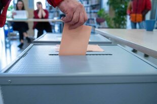 Ein Wähler steckt seinen Wahlschein in die Urne