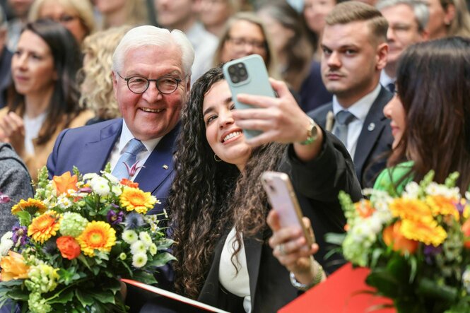 Frank-Walter Steinmeier lässt sich auf der Einbürgerungsfeier im Rathaus mit einer Bürgerin fotografieren.