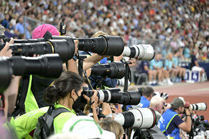 Viele Kameraobjektive von Sportfotografen, die sich auf einen nicht zu sehenden Wettkampf im Stadioninneren richten