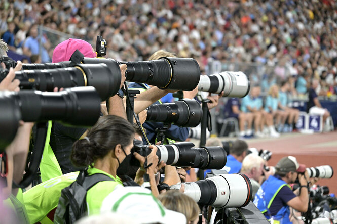 Viele Kameraobjektive von Sportfotografen, die sich auf einen nicht zu sehenden Wettkampf im Stadioninneren richten