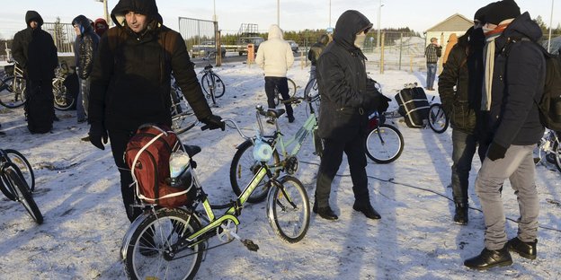 Menschen mit Fahrrädern stehen im Schnee