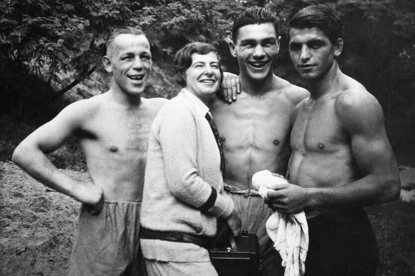 Eine Frau mit drei Männern oben ohne, in Sporthosen: Künstlerin Frieda Riess mit drei Boxern, in der Mitte Max Schmeling