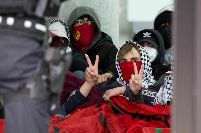 Vermummte Personen mit Pali-Tuch machen das Victory-Zeichen
