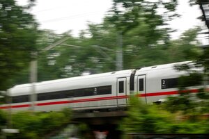 Ein ice-Hochgeschwindigkeitszug der Deutschen bahn fährt schnell durch ein bewaldetes Gebiet.