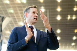 Ein Mann in blauem Anzug gestikuliert mit seinen Händen