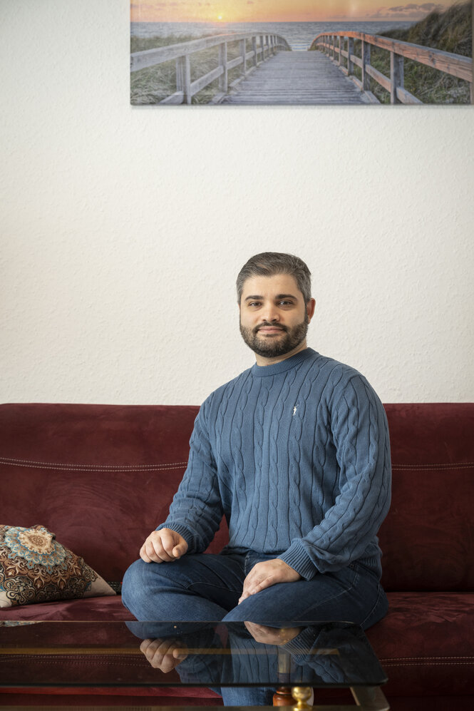 Ein Mann sitzt in seiner Wohnung auf dem Sofa