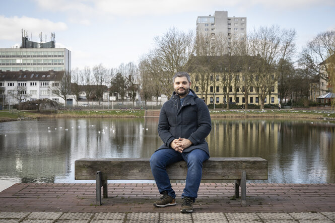 Ein Mann sitzt auf einer Bank an einem See in Bremerhaven