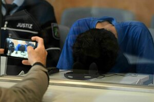 Eine Person hat ihren Kopf auf einen Tisch gelegt, eine weitere Person fotografiert diese Szene mit einem Handy