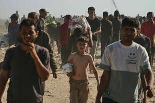 Strom an Menschen, die über Sandboden laufen und Lebensmittel bei sich tragen