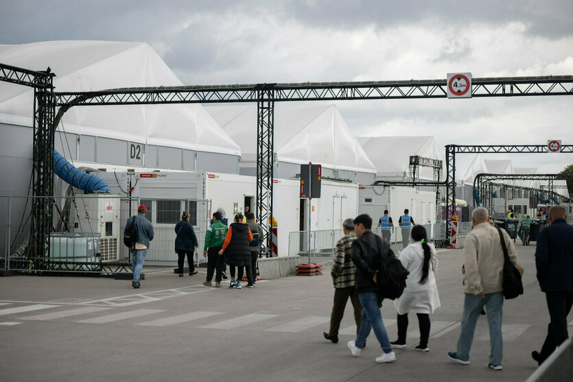 Menschen gehen zu den Großzelten der Flüchtlingsunterkunft Tegel