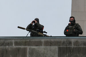 Zwei Männer in Uniform mit Fernrohren und kigelsicheren Westen stehen auf einem Dach