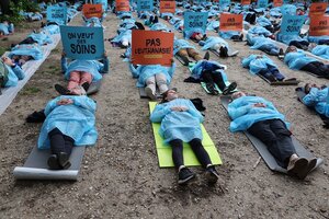 Menschen in blauer Schutzkleidung liegen auf der Erde