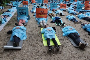 Menschen in blauer Schutzkleidung liegen auf der Erde