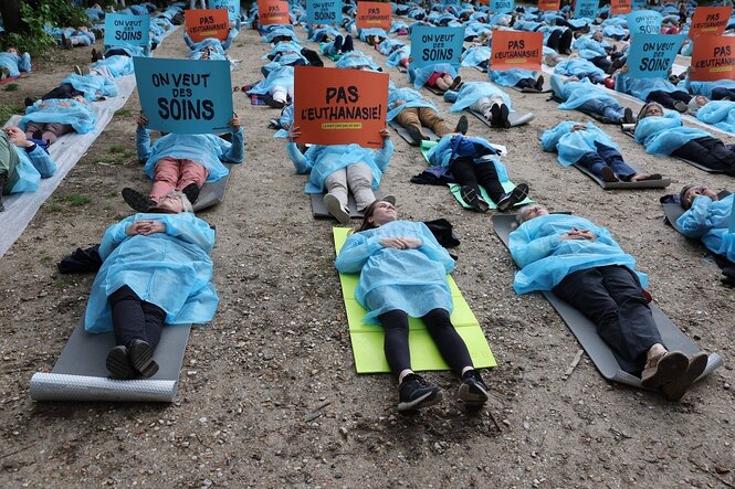 Menschen in blauer Schutzkleidung liegen auf der Erde