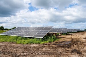 Eine Photovoltaikanlage auf einem Feld, auf dem Boden davor sieht man Spuren von Autoreifen