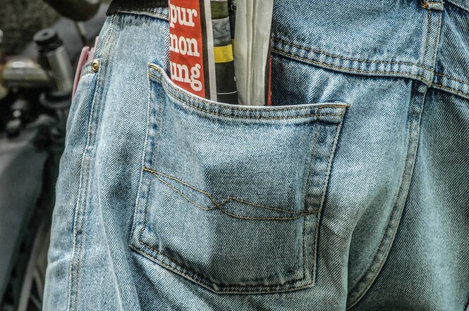 Eine Tageszeitung steckt in der Tasche einer Jeanshose