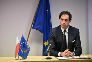Ein mann sitzt an einem Tisch, auf dem ein Europafähnchen steht