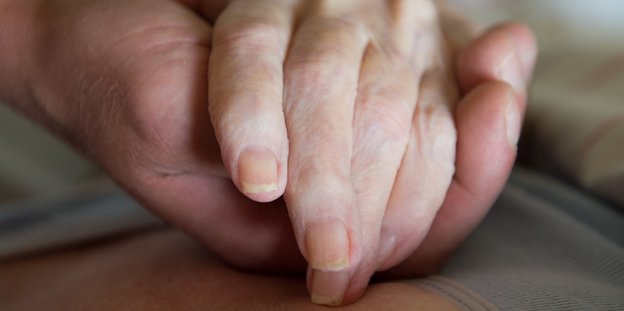 Altenpfleger hält Patientin die Hand