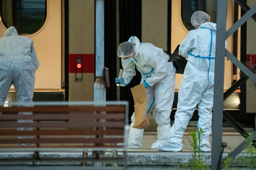 Personen in weißen Schutzanzügen untersuchen einen Tatort