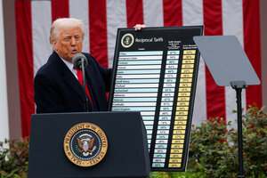 Donald Trump präsentiert auf einer Bühne eine Tabelle