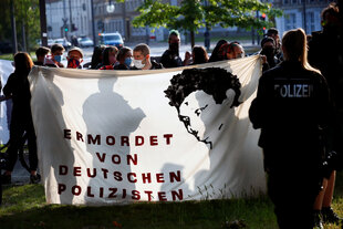 Menschen halten ein Transparent mit dem Bild von Oury Jalloh während einer Demonstration gegen Polizeibrutalität und Rassenungleichheit nach dem Tod von George Floyd im Polizeigewahrsam von Minneapolis in Dessau, Deutschland, 11. Juni 2020