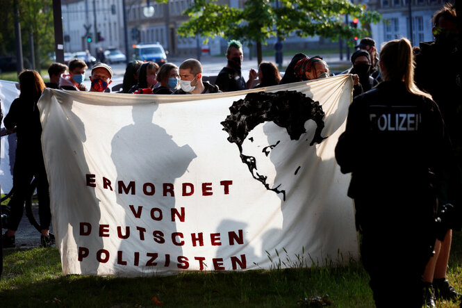 Menschen halten ein Transparent mit dem Bild von Oury Jalloh während einer Demonstration gegen Polizeibrutalität und Rassenungleichheit nach dem Tod von George Floyd im Polizeigewahrsam von Minneapolis in Dessau, Deutschland, 11. Juni 2020