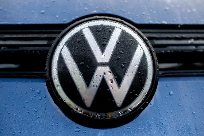 Volkswagen-Logo an einem blauen Auto im Regen.