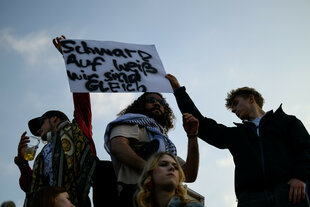 Demonstranten ein Schild mit der Aufschrift "Schwarz auf Weiß - wir sind gleich" hoch
