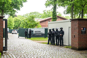 Polizisten stehen vor dem Eingang eines Reiterhofs