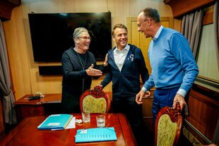 Bundeskanzler Friedrich Merz (r, CDU), Keir Starmer (l), Premierminister von Großbritannien, und Frankreichs Präsident Emmanuel Macron stehen im Salonwagen des Sonderzugs nach Kiew zusammen