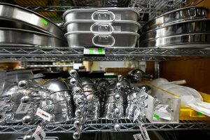 Küchenutensilien aus Stahl und Aluminium in einem Regal