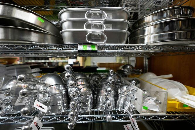 Küchenutensilien aus Stahl und Aluminium in einem Regal