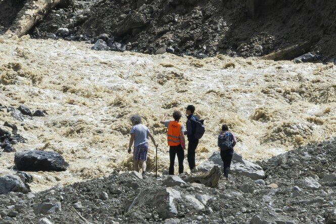 Vier Menschen stehen vor einem Naturpanorama voller Schlamm
