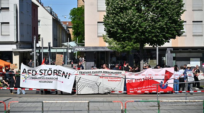 Mehrere Menschen stehen hinter Transpis mit Anti-AfD-Sprüchen auf einem Bürgersteig vor Hausfassaden