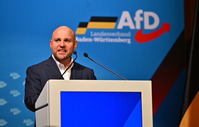 Markus Frohnmaier am Rednerpult vor einem blauen Hintergrund mit Parteilogo