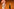 Zwei Menschen mit ausladenden Hüten vor orangem Hintergrund