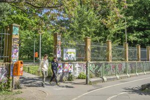 Mauer mit Zaunkrone, Menschen gehen durch ein Tor