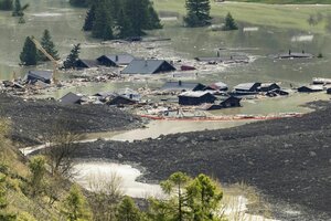 Die Dächer der Häuser des zerstörten Dorfes Blatten ragen aus Schlammwasser und Schutt