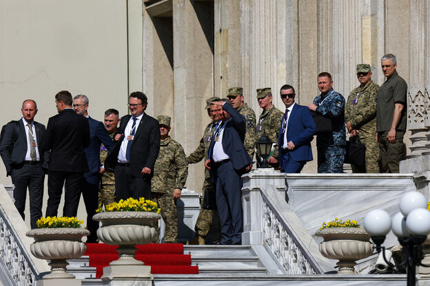 Männer in Uniformen und Anzügen stehen auf einer Treppe